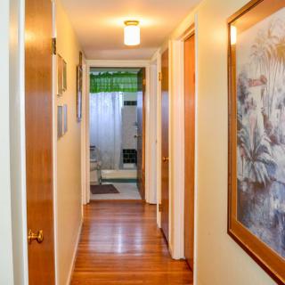 A cozy hallway with wooden floors, artwork on the walls, and doors leading to various rooms.