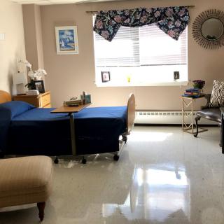 A bright and neatly arranged bedroom with a hospital bed by the window.