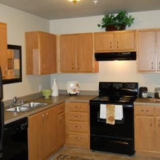 A modern kitchen with wooden cabinets and black appliances.