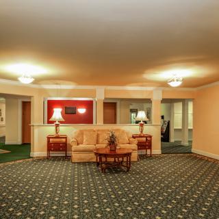 A warmly lit hotel lobby with a central seating area featuring a sofa and side tables.