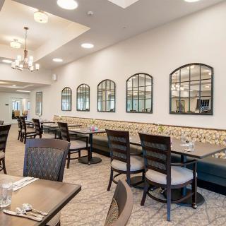 Modern dining area with neatly arranged tables and chairs, featuring decorative mirrors on the wall.