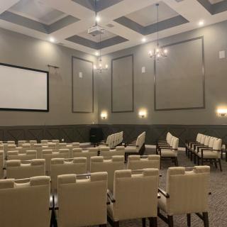 A modern conference room with rows of seating and a large projector screen.