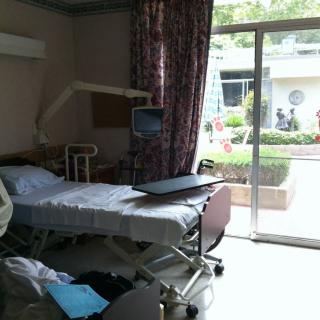 A hospital room with a bed, medical equipment, and a view through the window.