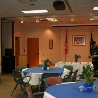 An indoor event room set up with tables and chairs, decorated for a gathering.