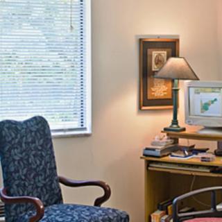 A cozy office setup with a computer on the desk, a comfortable chair, and a lamp providing soft lighting.