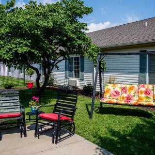 A cozy backyard patio with colorful garden furniture and a swing under a tree.