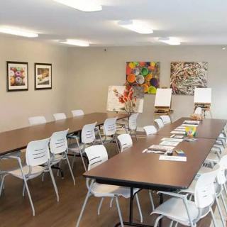 A well-lit meeting room with tables, chairs, and colorful artwork on the walls.