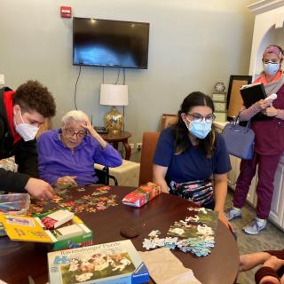A group of people involved in a puzzle activity at an elderly care facility.