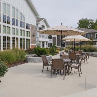A spacious patio area with tables, chairs, and umbrellas outside a modern building.