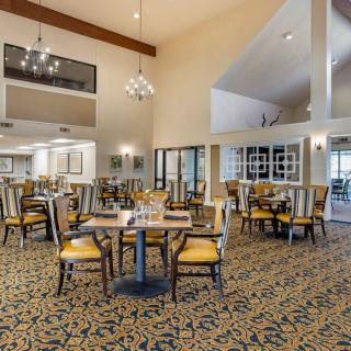 A spacious dining area with elegant decor, featuring tables and chairs under chandeliers.