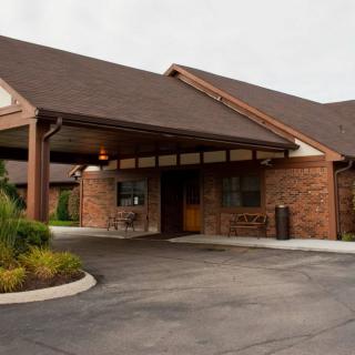 A brick building with a covered entrance and neatly landscaped surroundings.