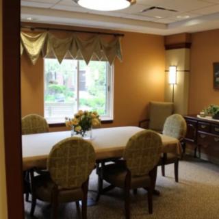 A cozy dining room with a large table and chairs, illuminated by natural light from the window.