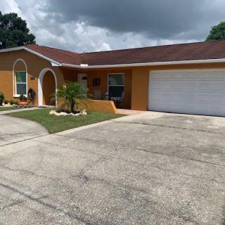 A single-story house with a garage and driveway under a cloudy sky.