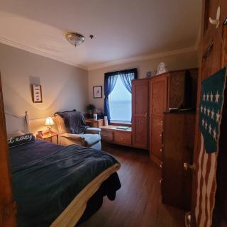 A cozy bedroom with a neatly made bed, wooden furniture, and soft lighting.