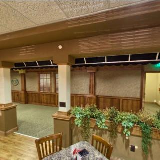 A cozy restaurant interior featuring wood paneling and a seating area adorned with plants.