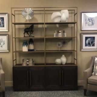 A stylish room interior featuring a shelving unit adorned with decorative items and surrounded by framed artwork.