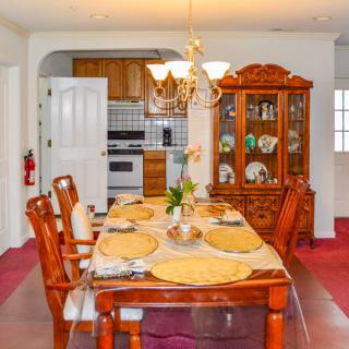 Elegant dining room with a set dining table, chandelier, and view into the kitchen.