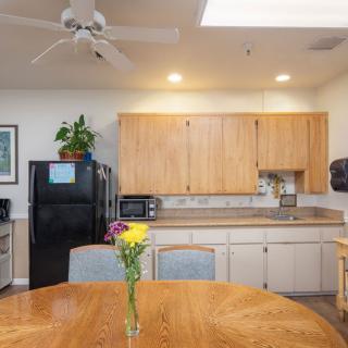 A cozy kitchen area with wooden cabinets and a dining table decorated with flowers.