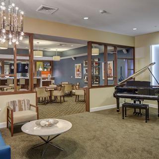 A modern living room featuring a grand piano, elegant chandelier, and comfortable seating.