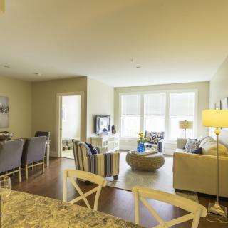 A spacious and well-lit living room with an open dining area, featuring modern furniture and large windows.