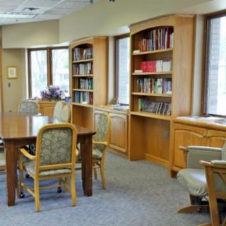 A quiet library room with bookshelves and a table surrounded by chairs.