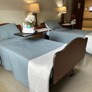 A view of a patient room featuring two hospital beds, each with decorative elements and warm lighting.