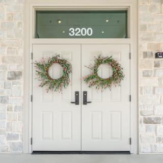 A set of double front doors adorned with wreaths, featuring the house number 3200 above.