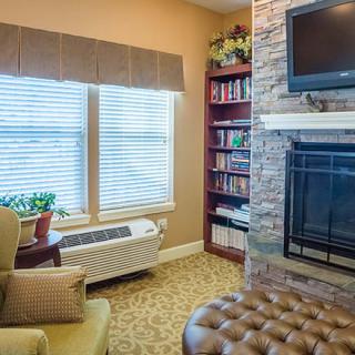 A cozy living room with a fireplace, television, and bookshelf.