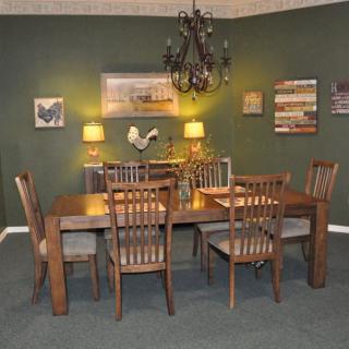 A cozy dining room with wooden furniture, a chandelier, and green walls adorned with art and lighting.
