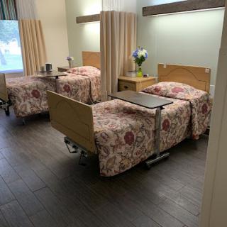 A view of a hospital room with two neatly made beds and a small table.