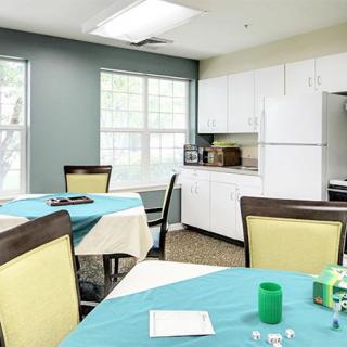 A bright dining area with tables, chairs, and a kitchenette.