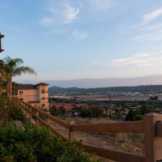 A scenic view of a residential area with buildings overlooking hills and a clear sky during sunset.