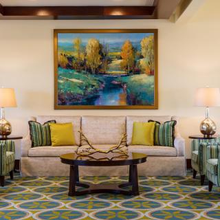 A well-decorated living room featuring a comfortable sofa, vibrant painting, and elegant lamps.