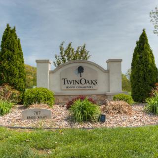 Entrance sign for Twin Oaks subdivision surrounded by landscaping and trees.