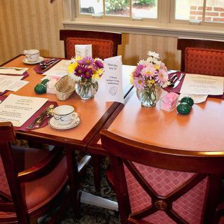 A neatly arranged dining table with flowers, menus, and tea cups in a restaurant setting.