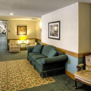 A cozy hotel lobby featuring a sofa, carpeted floors, and framed artwork on the walls.