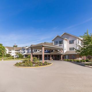 A view of a residential building with a driveway and landscaped entrance under a clear blue sky.