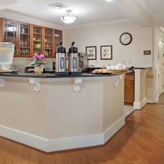 A cozy coffee station with a counter, featuring tea and coffee dispensers, set in a warmly decorated interior.