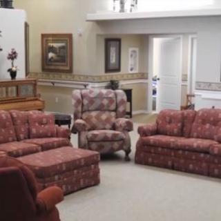 A cozy living room with floral patterned sofas and an armchair, surrounded by paintings and home decor.