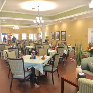 A spacious dining area with neatly arranged tables and chairs, illuminated by elegant overhead lighting.