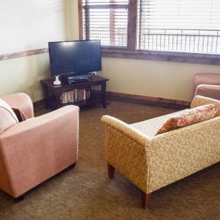A cozy living room with a sofa, armchair, and a TV near a window.