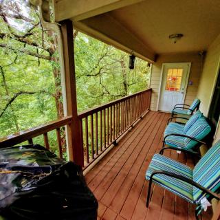 A cozy balcony with seating overlooking a lush forest.
