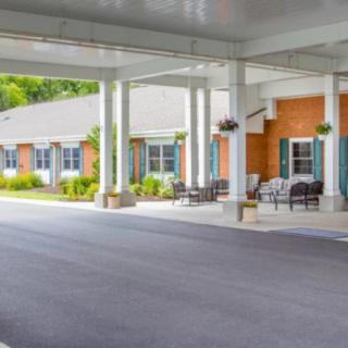A building entrance with a covered driveway and outdoor seating.