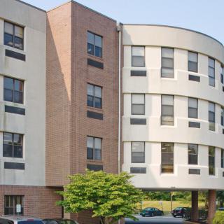 A modern apartment building with a unique curved design and multiple windows.