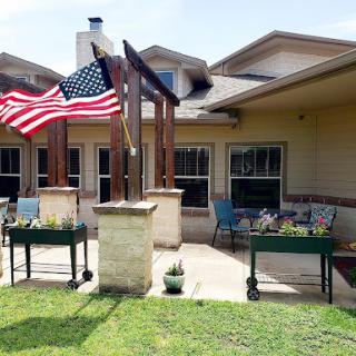 A cozy outdoor patio featuring an American flag, planters, and seating for relaxation.