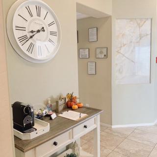 A cozy entryway featuring a wall clock, coffee station, and decorative wall art.