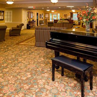 A grand piano in a cozy hotel lobby with comfortable seating and elegant decor.