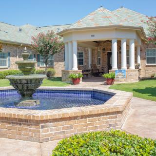 A beautifully landscaped garden with a central fountain and gazebo.