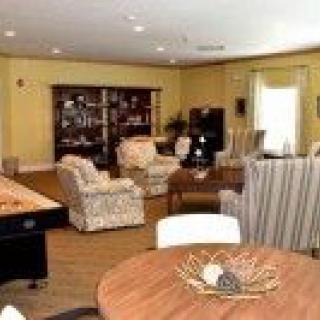 A cozy living room with a variety of furniture including sofas, chairs, a table, and a bookshelf, all set on hardwood flooring.