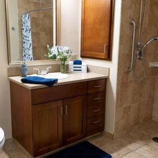 A well-organized bathroom with a wooden vanity, mirror, and walk-in shower.